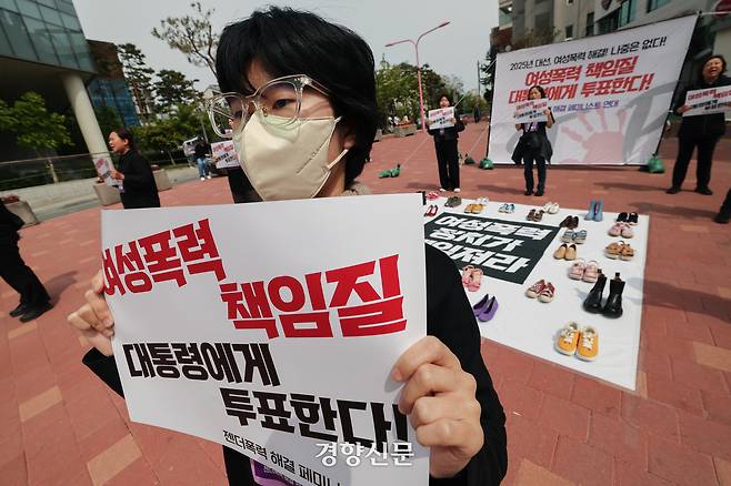 서울여성회 페미니스트 대학생연합동아리 회원들이 지난달 27일 서울 마포구 홍대입구역 앞에서 열린 ‘2025 대선, 여성폭력 해결! 나중은 없다!’ 캠페인에서 여성폭력 희생자들을 상징하는 신발을 놓고  다이-인(Die-in) 퍼포먼스를 하고 있다. 성동훈 기자