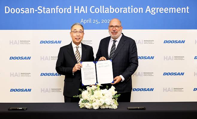 Doosan Group Vice Chairman Park Gee-won (left) and James Landay, co-founder and co-director of the Stanford Institute for Human-centered Artificial Intelligence, pose for a photo after signing a collaboration agreement at the Doosan headquarters in Seoul on April 25. (Doosan Group)