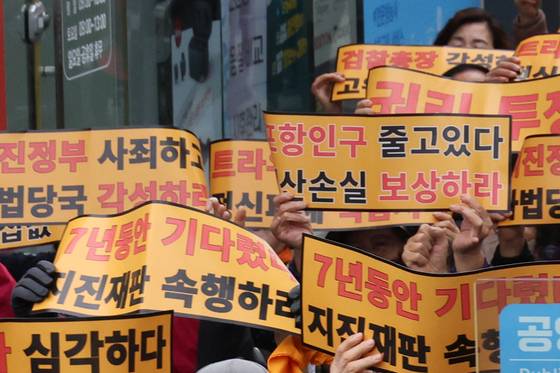 Participants hold signs urging progress in the trial during a citizens' rally organized by the Pohang Earthquake Citizens' Countermeasure Headquarters and 120 social, religious and volunteer groups at Pohang Jungang Market in Pohang, North Gyeongsang on Nov. 15, 2024. [YONHAP]