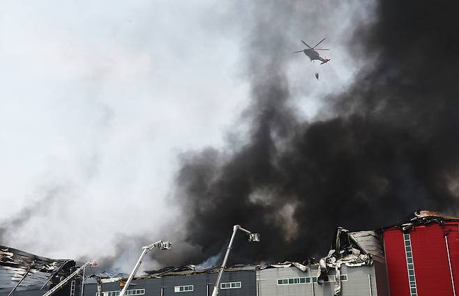 13일 경기도 이천시 부발읍 소재 대형 물류창고에서 불이 나 소방헬기가 진화작업을 하고 있다. [연합]