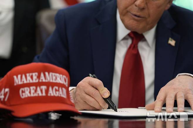 [워싱턴=AP/뉴시스] 도널드 트럼프 미국 대통령이 지난달 23일(현지 시간) 백악관 집무실에서 교육 관련 행정명령에 서명하는 동안 '미국을 다시 위대하게'(MAGA) 구호가 적힌 모자가 책상 위에 올려져 있다. 2025.05.13.