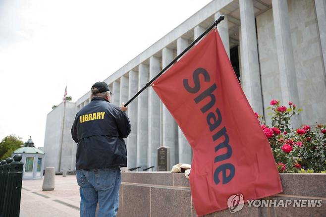 "수치" 12일(현지시간) 미 워싱턴DC 의회도서관 밖에 한 남성이 '수치'라고 쓰인 붉은 깃발을 들고 서 있다. [AFP=연합뉴스 자료사진. 재판매 및 DB 금지]