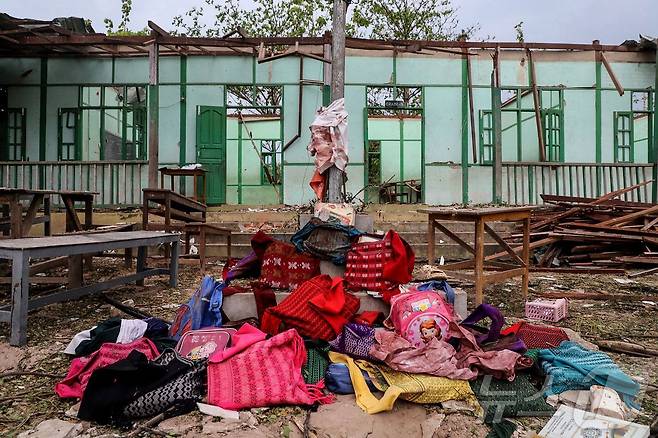 12일(현지시간) 미얀마 사가잉 지역 데파인타운십의 오헤 테인 트윈 마을에서 미얀마군의 폭격으로 파괴된 학교 앞에 희생자들의 유품이 놓여 있다.  ⓒ AFP=뉴스1