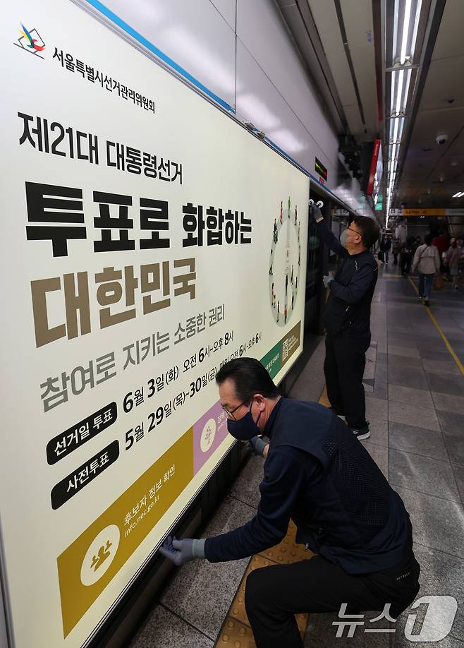 제21대 대통령선거를 20일 앞둔 14일 오전 서울 종로구 지하철 혜화역 승강장 스크린도어에 선관위 관계자들이 대선 홍보물 래핑작업을 하고 있다. 2025.5.14/뉴스1 ⓒ News1 박세연 기자