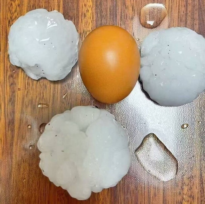 13일 저녁 중국 베이징에 내린 우박들을 달걀과 비교한 사진. [사진 = 웨이보]