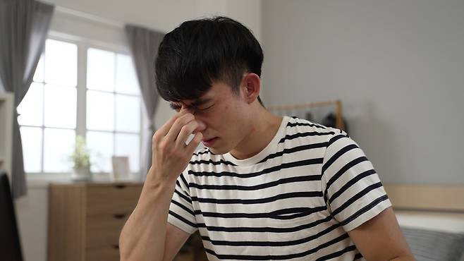 침대에 앉아있는 남성 [123rf]