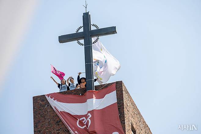 4월18일부터 서울 종로구 혜화동성당 종탑에서 고공 농성 중인 민푸름, 박초현, 이학인 탈시설 운동 활동가(왼쪽부터)가 4월28일 카메라를 향해 손을 흔들고 있다.ⓒ시사IN 박미소
