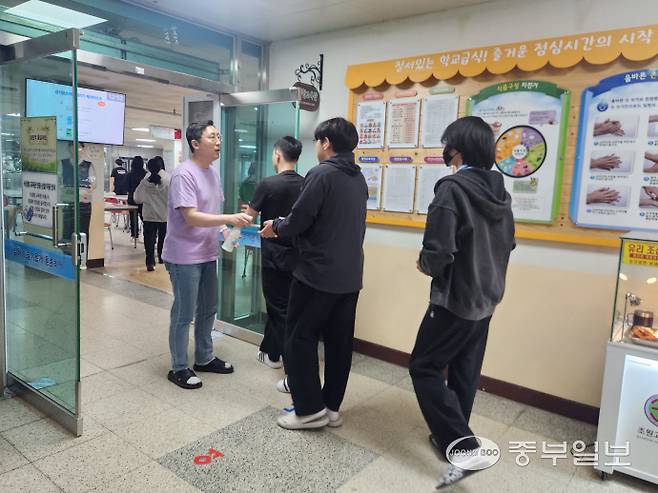 조원고등학교 교사가 급식실 앞에서 학생들에게 손소독제를 직접 뿌려주고 있다. 신연경기자