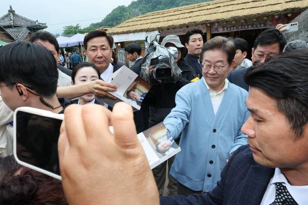 더불어민주당 이재명 대선 후보가 15일 하동군 화개장터 입구서 유튜브 'K-이니셔TV 케미폭발 동서화합 화개장터 라이브' 오프닝 후 지지자가 건네준 책에 사인을 해주고 있다. 연합뉴스
