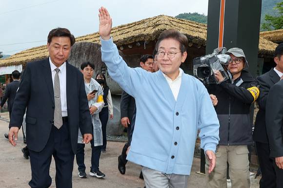 이재명 더불어민주당 대선후보가 15일 경남 하동군 화개장터 입구에서 유튜브 'K-이니셔TV 케미폭발 동서화합 화개장터 라이브' 오프닝을 마친 후 이동하며 인사하고 있다. [사진=연합뉴스]