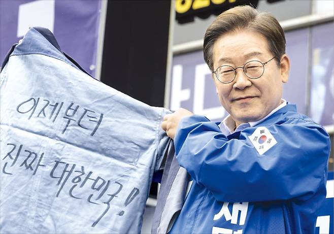 < 창원서 작업복 받은 이재명 >  이재명 더불어민주당 대선 후보가 14일 경남 창원 상남분수광장 유세에서 작업복을 들어 보이고 있다. 이날 부산에서 일정을 시작한 이 후보는 창원 통영 거제 하동 등 ﻿지역에서 유권자들을 만났다.  연합뉴스