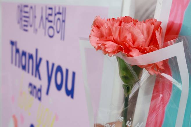 스승의날인 15일 서울 성동구 서울방송고등학교에서 등교하는 학생들을 맞이하는 교사가 카네이션과 손팻말을 들고 있다. [연합뉴스]