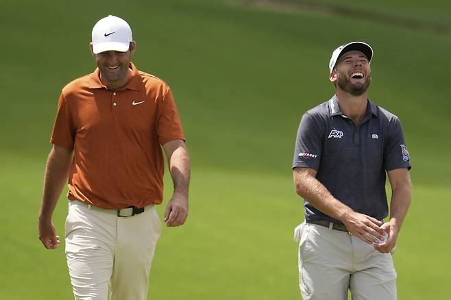 오렌지색 셔츠를 입은 스코티 셰플러(왼쪽)가 15일 미국 노스캐롤라이나주 샬럿의 퀘일 할로 클럽에서 열린 PGA 챔피언십 연습라운드에서 샘 번스와 함께 대화하며 크게 웃고 있다.  샬럿｜AP연합뉴스