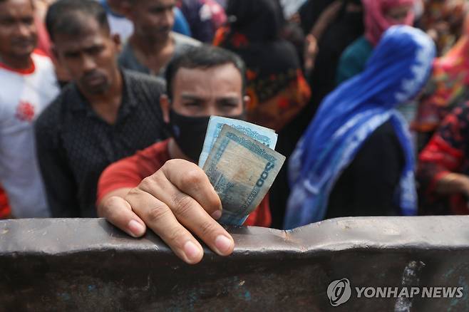 방글라데시 경제 지난 2월 18일 방글라데시 수도 다카에서 한 남성이 자국 화폐 '타카'를 들고 방글라데시 무역공사가 할인 판매하는 생필품을 사기 위해 기다리고 있다.
[EPA 연합뉴스 자료사진. 재판매 및 DB 금지