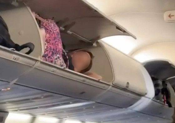 한 여성이 항공기 짐칸에 누워 있다. 틱톡 캡처