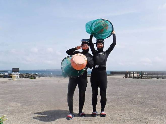 태왁과 망사리를 들고 기념 사진을 찍는 관광객