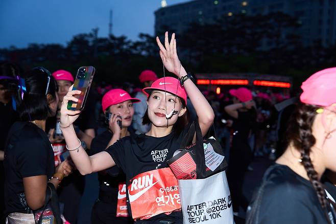 지난 10일 서울서 열린 '나이키 애프터 다크 투어 서울10K에서 한 참가자가 레이스가 끝난 뒤 축제에 앞서 메달을 찍어보이고 있다./나이키