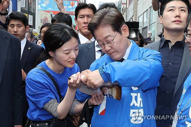 사인하는 이재명 후보 (대구=연합뉴스) 김주성 기자 = 더불어민주당 이재명 대선 후보가 13일 '보수의 심장'이라고 불리는 대구광역시의 동성로 거리에서 집중 유세를 마친 후 여성당원 김희정 씨에게 사인을 해주고 있다. 2025.5.13 [공동취재] utzza@yna.co.kr