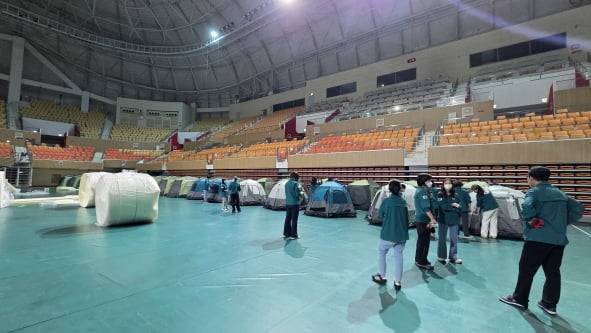 17일 오전 발생한 금호타이어 광주공장 화재 여파로 검은 연기가 퍼지면서 대피를 희망하는 주민들을 위해 광산구 공무원들이 광주여대 체육관에 400세대를 수용할 수 있는 텐트를 설치하고 있다. 광산구 제공