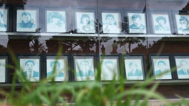 16일 광주 북구 망월동 민주민주열사묘역 행방불명자 영정 뒤로 참배객들이 비치고 있다.