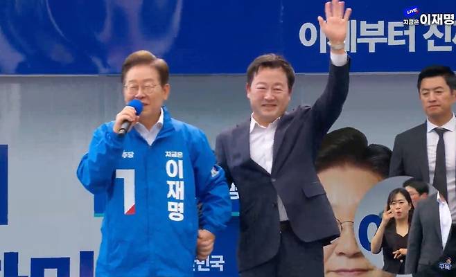 이재명 더불어민주당 대선 후보가 17일 광주 김대중컨벤션센터 광장에서 진행된 유세에서 김용남 전 새누리당 의원을 소개하고 있다. 이 후보는 김 전 의원과 포옹하고, 손도 꼭 잡았다. 더불어민주당 유튜브 ‘델리민주’ 캡처