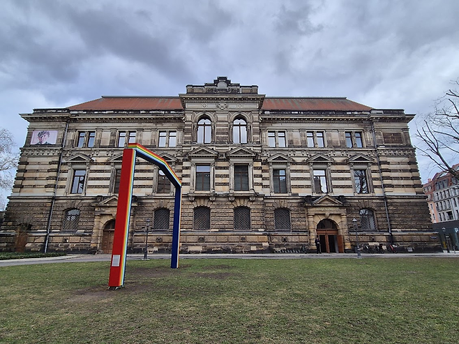 거대한 현대미술관 알버티눔 우측의 모습. 공원에는 설치된 마렉 솝치크의 직사각형 무지개 형태의 문 조각, [예술가의 예우]. 미술관의 포용성을 상징하며 2024년 설치됐다. ©김슬기