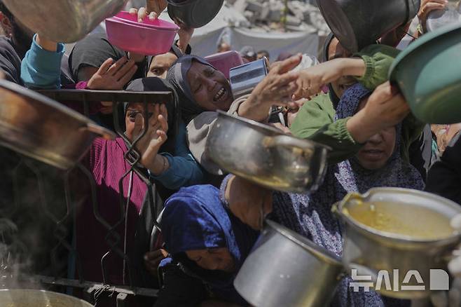 [베이트 라히야=AP/뉴시스] 29일(현지 시간) 가자지구 북부 베이트 라히야의 한 배급소에서 팔레스타인 주민들이 구호 음식을 받고 있다. 2025.04.30.