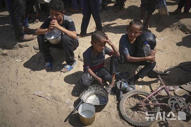 [칸유니스=AP/뉴시스] 9일(현지 시간) 가자지구 남부 칸유니스에서 팔레스타인 어린이들이 식기를 들고 음식 배급을 기다리고 있다. 2025.05.10.