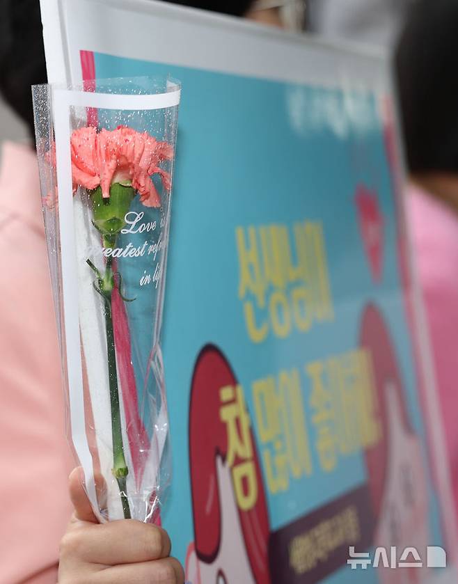 [서울=뉴시스] 김명년 기자 = 스승의 날인 15일 오전 서울 성동구 서울방송고등학교에서 선생님이 카네이션을 들고 등교하는 학생들을 맞이하고 있다. 2025.05.15. kmn@newsis.com