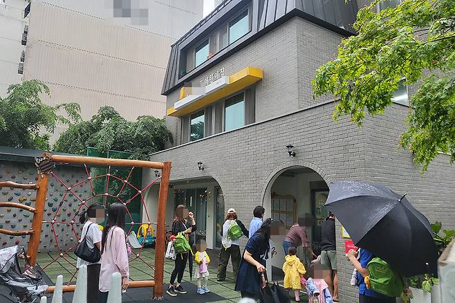 비 오는 오후, 하원 시간에 맞춰 부모들이 하나둘 어린이집을 찾는다. 하루하루 전쟁 같은 육아 속에서, 어린이집은 부모에게 잠시 숨을 고를 수 있는 오아시스 같은 공간이다.