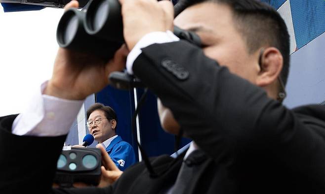 더불어민주당 이재명 대선후보가 16일 전북 군산시 구시청광장에서 열린 유세에서 지지를 호소하는 연설을 하는 가운데 경호원이 경계 근무를 서고 있다. 공동취재