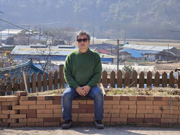 ﻿고성 자택 마당에 앉은 동길산 시인. 그는 "시인의 색깔이 있다면 이파리 다 떨어진 감나무 가지에 가깝다"고 말한다.