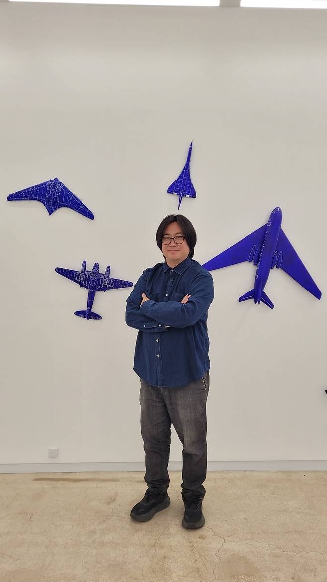 신기운 작가가 자신의 작품들 앞에서 포즈를 취하고 있다.