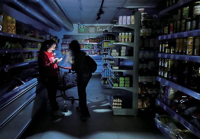 스페인 대정전의 날, 바르셀로나의 한 슈퍼마켓에서 종업원이 손전등으로 고객을 도와주는 모습 ⓒ로이터 연합
