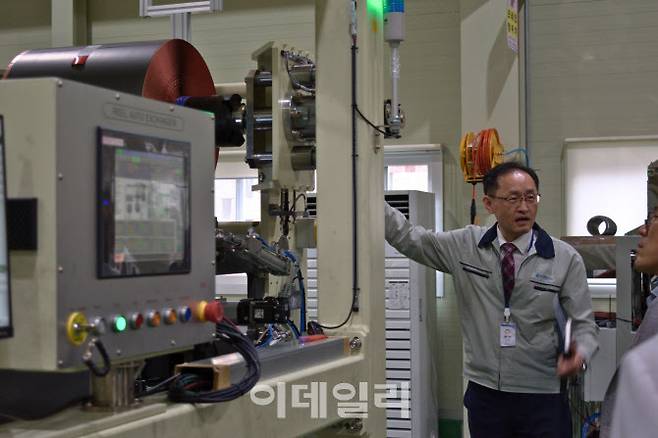 고강호 엠플러스 기술연구소장(전무)가 엠플러스 공장에서 전극 자동 공급 장비에 대해 설명하고 있다. (사진=엠플러스)