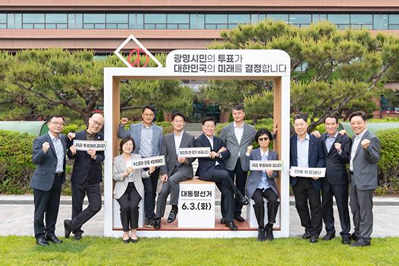 박승원 광명시장(왼쪽 여섯번째) 등이 19일 시청 앞 잔디 광장에 설치된 투표 참여 조형물에서 기념 촬영을 하고 있다. [사진=광명시]