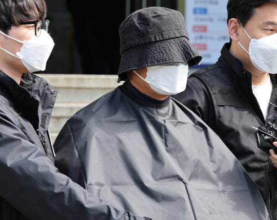 부산 법원 앞에서 생방송하던 유튜버를 살해한 혐의(특가법상 보복살인)를 받는 50대 유튜버가 지난해 5월 오전 부산 연제경찰서에서 검찰 송치를 위해 이동하고 있다. 연합뉴스