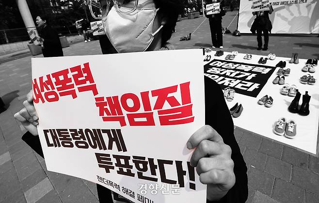 서울여성회 페미니스트 대학생연합동아리 회원들이 27일 서울 마포구 홍대입구역 앞에서 열린 ‘2025 대선, 여성폭력 해결! 나중은 없다!’ 캠페인에서 여성폭력 희생자들을 상징하는 신발을 놓고  다이-인(Die-in) 퍼포먼스를 하고 있다. 성동훈 기자