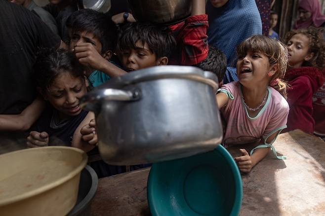 18일(현지시간) 가자지구의 한 식량 배급소에서 팔레스타인 아이들이 음식을 호소하며 냄비를 들어보이고 있다. EPA연합뉴스