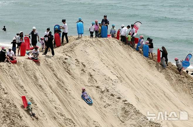 [부산=뉴시스] 하경민 기자 = '2025년 해운대 모래축제'가 열린 18일 부산 해운대구 해운대해수욕장에서 시민과 관광객들이 샌드보드를 즐기고 있다. 오는 19일까지 열리는 이번 축제에는 14명의 해외 모래 작가가 제작한 총 20여 개의 모래작품을 선보이며, 축제가 끝난 이후에도 6월8일까지 모래작품을 전시한다. 2025.05.18. yulnetphoto@newsis.com
