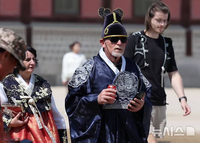 [서울=뉴시스] 김명원 기자 = 18일 서울 종로구 경복궁에서 왕의 복장을 한 외국인 관광객들이 음료를 들고 이동하고 있다. 2025.05.18. kmx1105@newsis.com