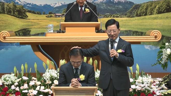 최선길 원로목사가 7대 담임으로 부임한 최규완목사를 위해 안수기도 하는 모습. 최진성 아나운서