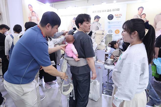 지난 1일 서울 강남구 코엑스에서 열린 2025 코베 베이비페어에서 관람객들이 아기띠를 착용해보고 있다. ⓒ연합뉴스