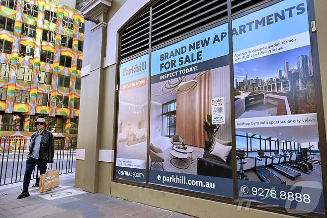 한 남성이 호주 멜버른의 새 아파트 광고판 앞을 지나가고 있다. 2025.5.20 ⓒ AFP=뉴스1