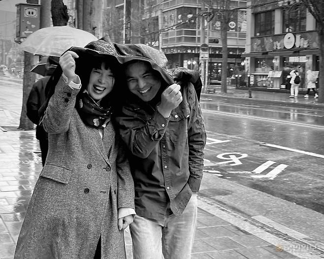 전신근(오른쪽) 목사와 제행신(왼쪽) 작가 부부가 지난해 서울 한 거리에서 외투로 비를 피하고 있다. 전신근 목사 제공