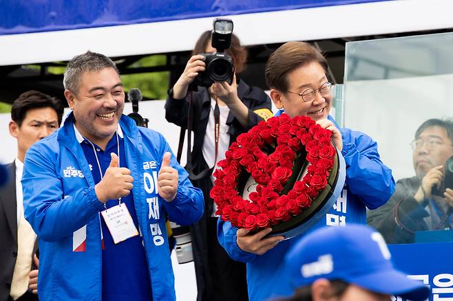 이재명 더불어민주당 대선 후보가 20일 경기 고양시 일산문화공원에서 장미꽃으로 만든 투표 기호를 들며 웃고 있다. 왼쪽은 이 후보 지원 유세에 나선 배우 이원종씨. 이 후보는 이날 “일산대교 통행료 무료화를 추진하겠다”고 했다./남강호기자