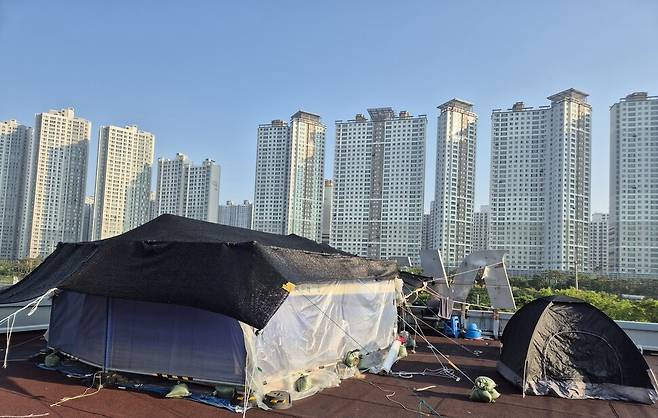 2025년 5월11일 경북 구미 한국옵티칼하이테크 출하동 옥상 고공농성장 모습. 맞은편에 대단지 아파트가 서 있다. 신다은 기자