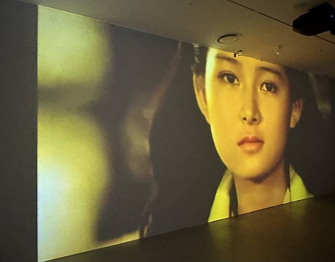 A large screen at the Atelier Ghana exhibition plays an early advertisement featuring actress Chae Shi-ra, along with other commercials from over the years. [WOO JI-WON]