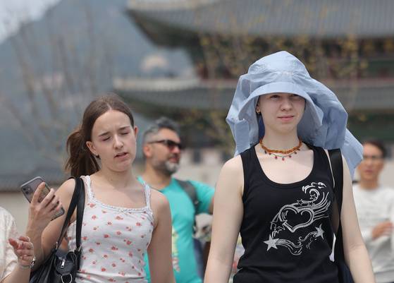 Tourists walk along Gwanghwamun Square in Jongno District, central Seoul in the heat as Seoul is seeing early summer weather on April 17. [YONHAP]