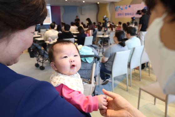 A baby holds an adult's hand during an education session for pregnant women at a hospital in Goyang, Gyeonggi. [YONHAP]